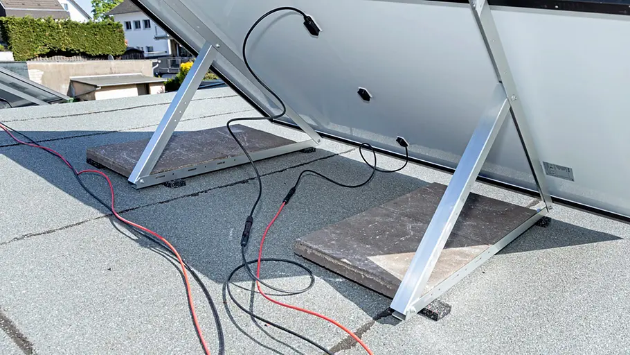 Kleine Solaranlage Zwei Solarpanels stehen auf einen Flachdach, sie sind mit Kabeln an Steinplatten befestigt.