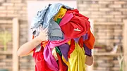 Frau trägt Kleiderhaufen - Foto: belchonock / iStock Frau trägt Kleiderhaufen - Foto: belchonock / iStock