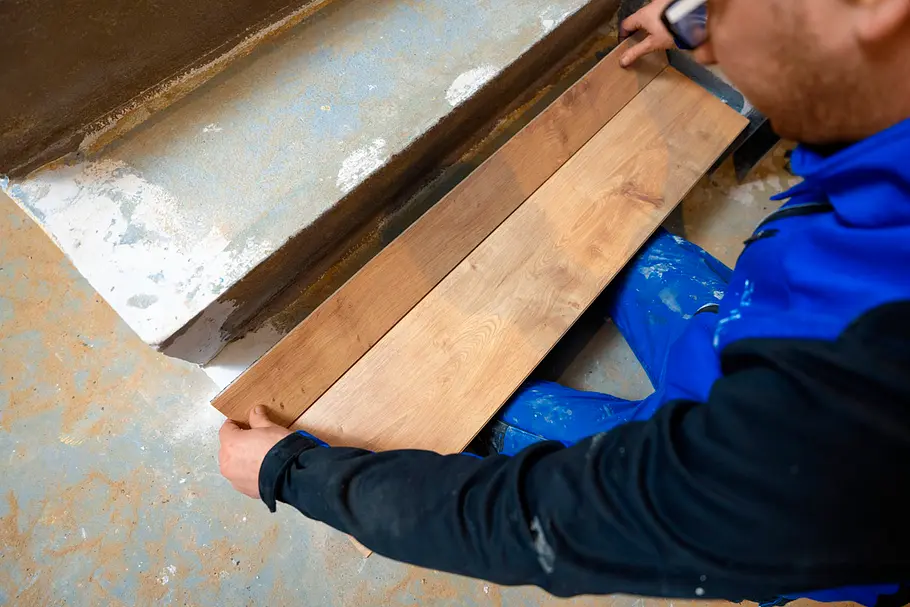 Person legt mehrere Laminatdielen testweise auf eine Treppenstufe.