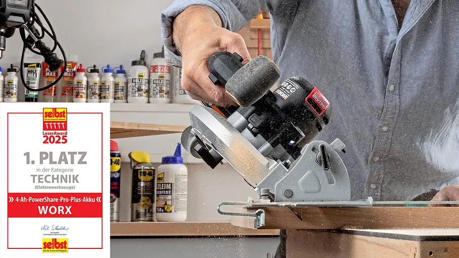 Leseraward Gewinner Elektrowerkzeuge Eine Person schneidet ein Holzbrett mit einer Akku-Handkreissäge von Worx in einer Werkstatt, umgeben von Holzleimflaschen.
