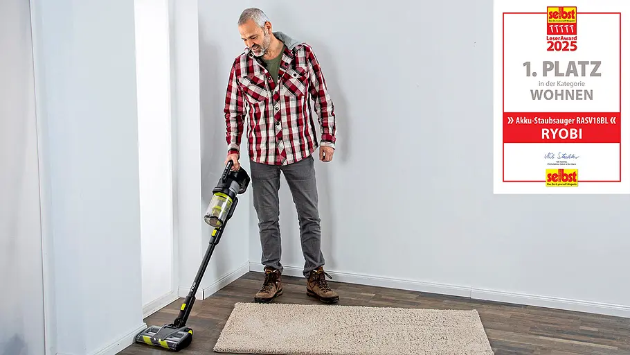 Leseraward Gewinner Wohnen Ein Mann mit grauen Haaren saugt mit einem Akku-Staubsauger von Ryobi einen Teppich in einem hellen Raum.