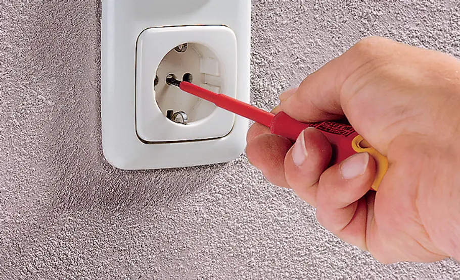 Lichtschalter wechseln Ein Schraubendreher wird angesetzt, um den Lichtschalter aus der Wand zu lösen