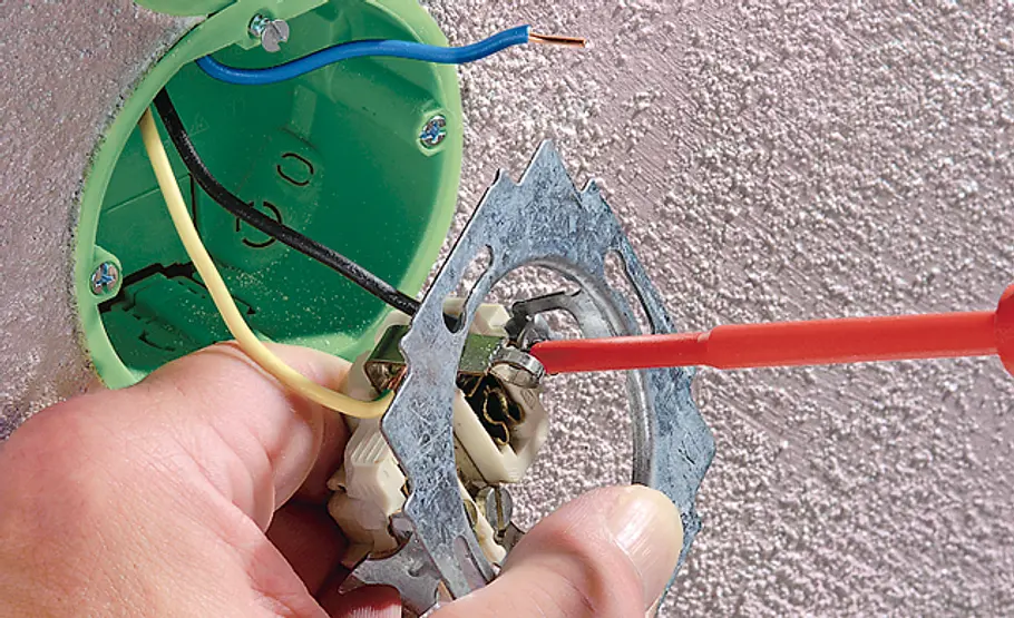 Lichtschalter wechseln Steckdose abklemmen: Schraubendreher löst Anschlüsse einer Steckdose, Kabel ragen aus der Dose.