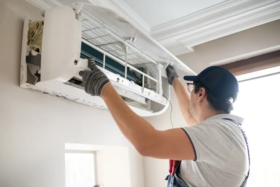 Einbau Luft-Luft-Wärmepumpe Ein Arbeiter baut die Inneneinheit einer Luft-Luft-Wärmepumpe in einem Zimmer ein.