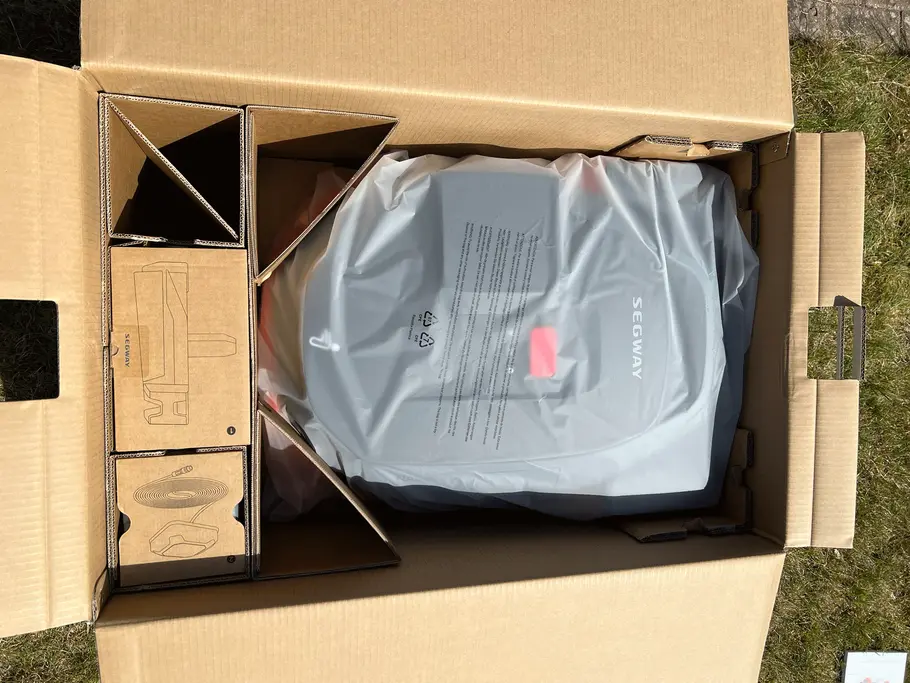 Der Mähroboter kam gut verpackt auf seinem Testgelände an. Eingepackter Mähroboter der Marke Segway in einem braunen Karton.