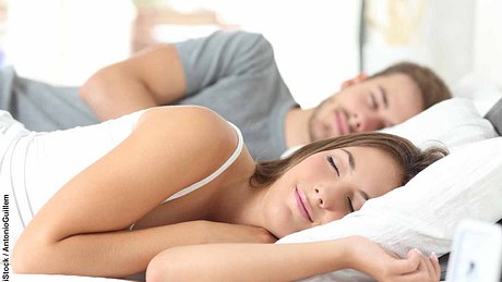 Mann und Frau schlafen glücklich in einem Bett - Foto: iStock / AntonioGuillem