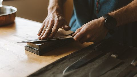 Ein Messer wird auf einem Schleifstein geschliffen - Foto: iStock / Wirestock