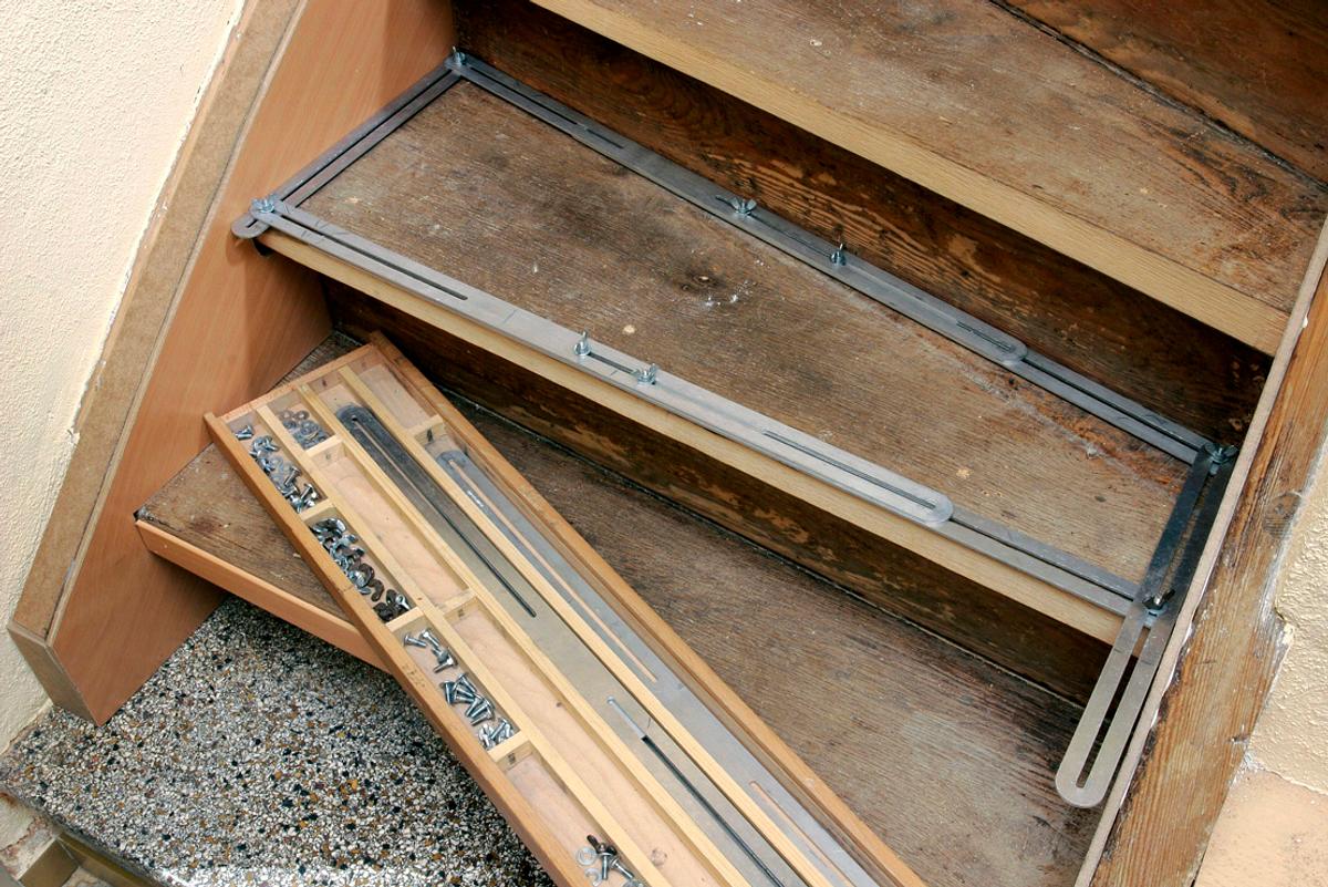 Metallleisten werden auf einer alten Treppe montiert, vorne liegt eine Werkzeugbox.