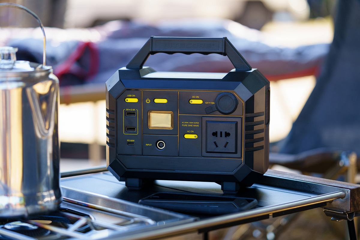 Eine typische Powerstation steht auf einem Campingkicker, es sind Anschlüsse und Bedienfelder zu erkennen