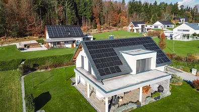 Einfamilienhäuser auf einer grünen Wiese mit PV-Anlagen auf den Dächern - Foto: istockphoto.com / Ziga Plahutar