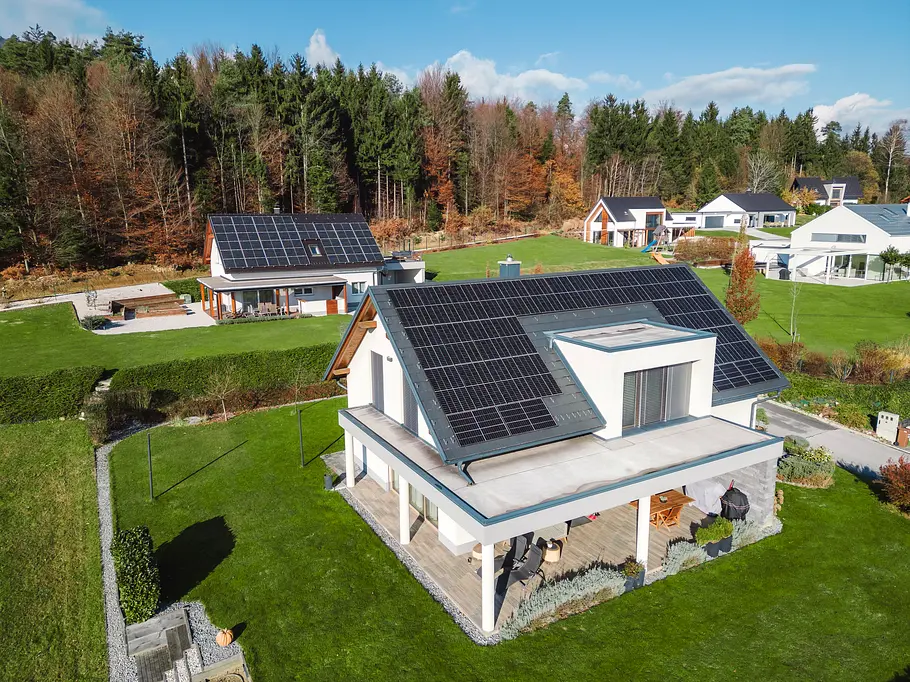 pv-anlage-dach-stromtarif Einfamilienhäuser auf einer grünen Wiese mit PV-Anlagen auf den Dächern