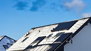 Einfamilienhaus mit Solarpanels auf dem Dach, es liegt Schnee und verdeckt einige der Panels - Foto: istockphoto.com / AHatmaker