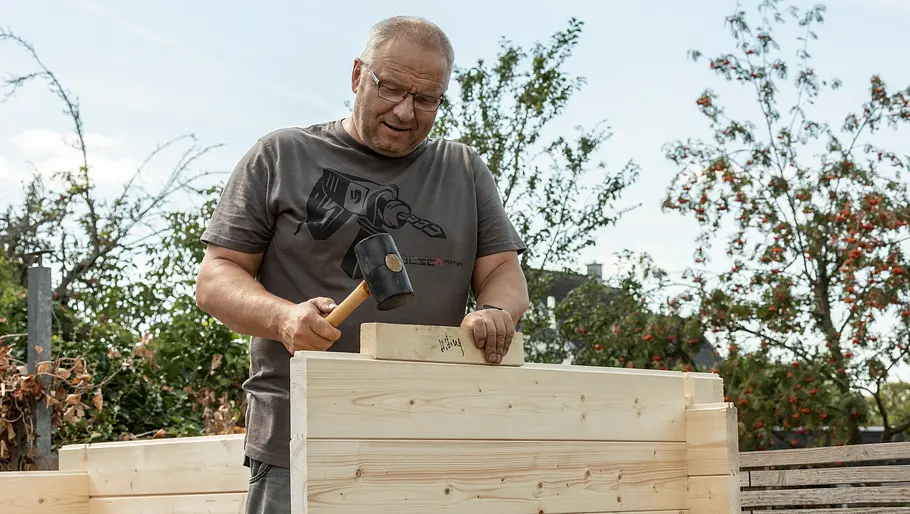 Restholzstück zwischen Bohle und Hammer legen Restholzstück zwischen Bohle und Hammer legen