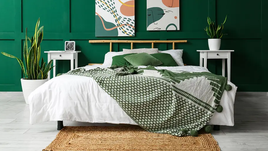 Schlafzimmer nach Feng Shui einrichten: das große Bett mit Bambus-Betthaupt hebt sich gut von der grün gestrichenen Wand ab.