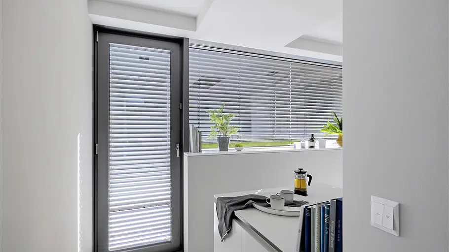 Smarte Beschattung Smarte Innenjalousien an großen Fensterflächen regulieren automatisch Tageslicht und Sichtschutz in einem modernen Wohnraum.