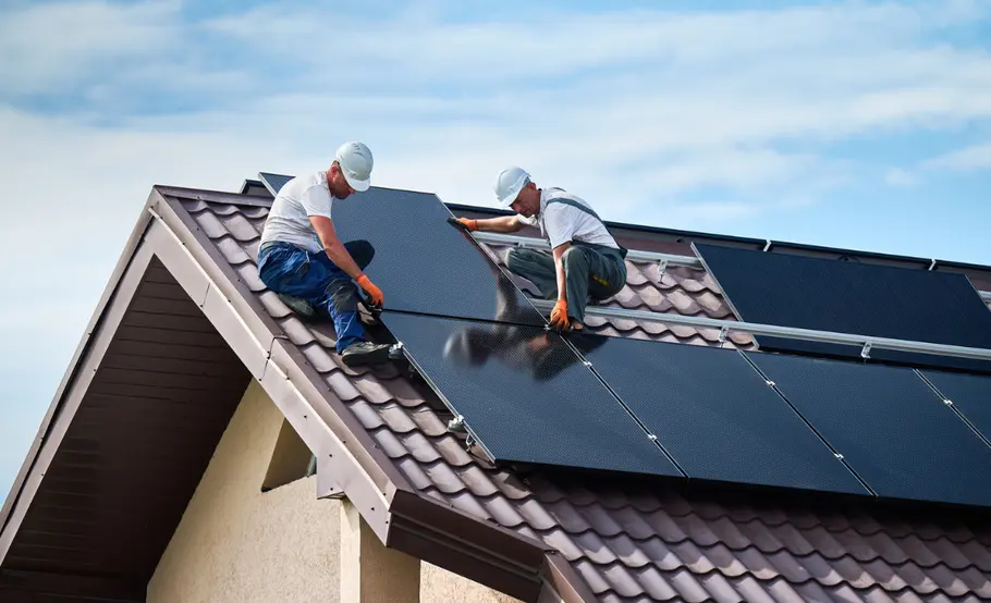 Solaranlage-Dach-Installation Zwei Männer bringen Solarmodule auf einem Dach an