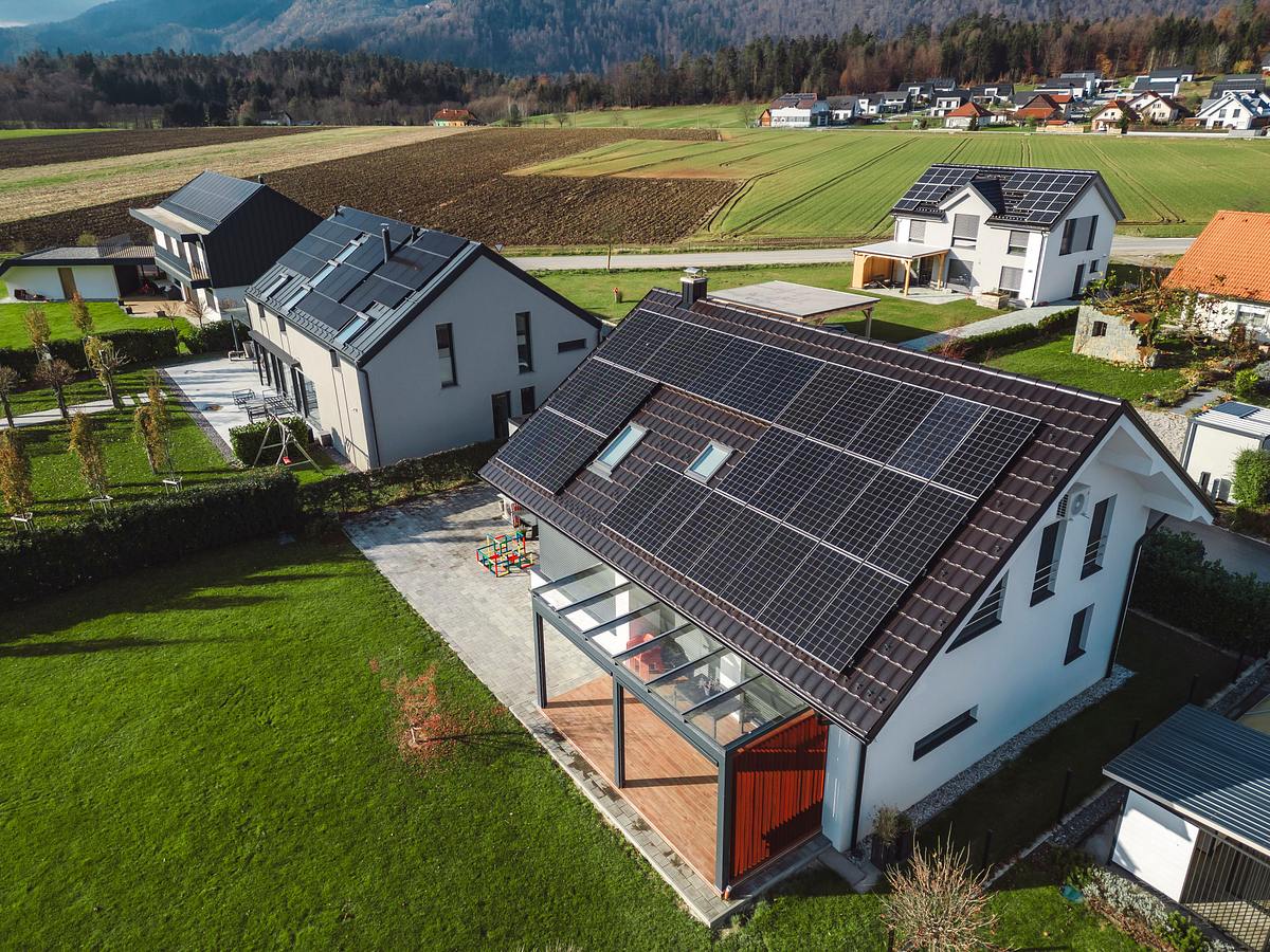 Niedrige Luftnahaufnahme neue dichte ländliche Wohnsiedlung, meist graue Dächer, etwas grüne Landschaftsgestaltung, junge Bäume. Moderne Häuser mit Flachdach