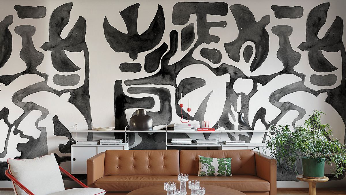 Ein Wohnzimmer mit einer braunen Couch und einer modernen Tapete in schwarz-weiß mit Vogelsilhouetten.