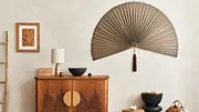 Feng-Shui-Tipps für die Wohnungseinrichtung: Ein asiatisccher Fächer dient als Wanddekoration über einer Holzkommode - Foto: iStock / FollowTheFlow
