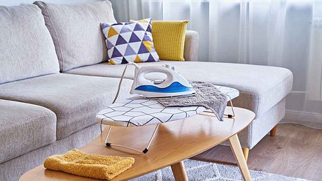 Bügeleisen steht auf einem Tischbügelbrett auf dem Tisch. - Foto: iStock / Kira-Yan