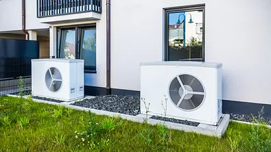 Zwei Wärmepumpen stehen vor einer weißen Hausfassade - Foto: istockphoto.com / brebca