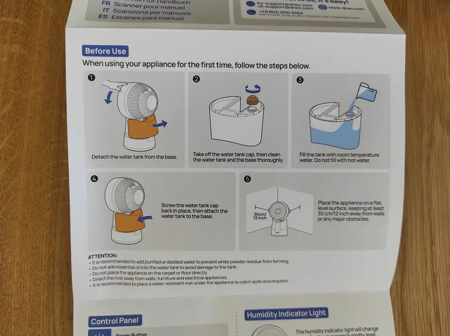 De Kurzanleitung zeigt anschaulich, wie der Wassertank vor der ersten Nutzung befüllt werden muss. Eine bebilderte Anleitung zum Befüllen des Wassertanks des DREO TurboCool liegt auf einem Holztisch.