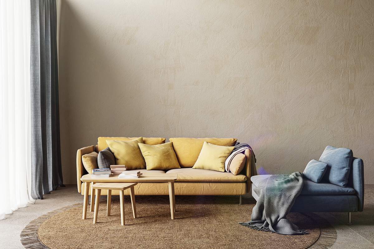 Ein gelbes Sofa und ein blauer Sessel vor einer beigen Wand