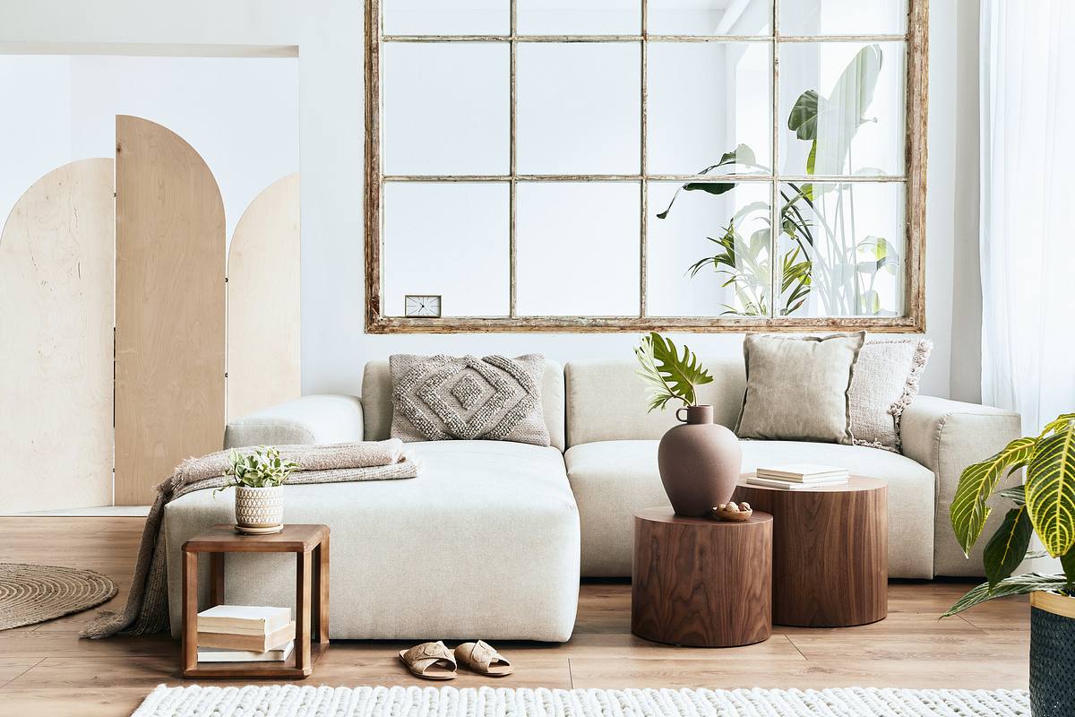 Ein modern eingerichtetes Wohnzimmer: Neutrale Farben wie Beige und Wollweiß treffen auf Walnussholz und große Zimmerpflanzen