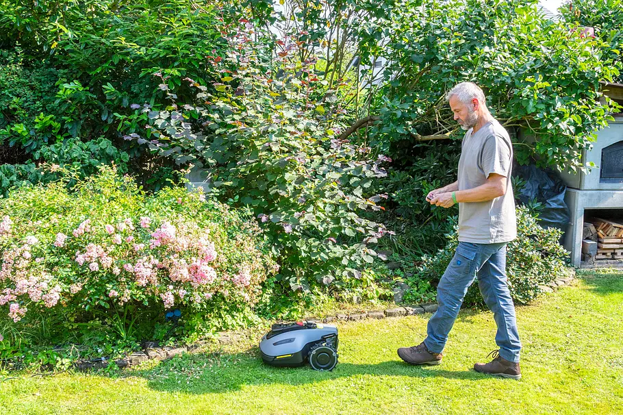 Erster Einsatz des Mähroboters Mann begleitet den Yuka Mini 800 Mähroboter beim ersten Einsatz entlang einer Hecke im Garten.